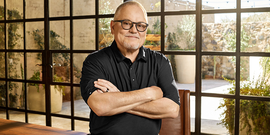 Bob Parsons stands wearing a black T-shirt bwith his arms folded
