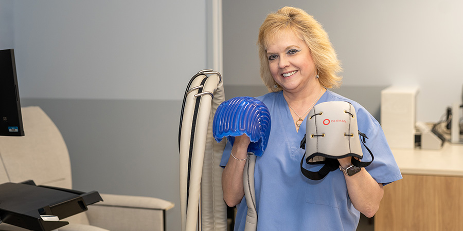Infusion nurse Dawn holds a scalp cooling device used in cancer treatment