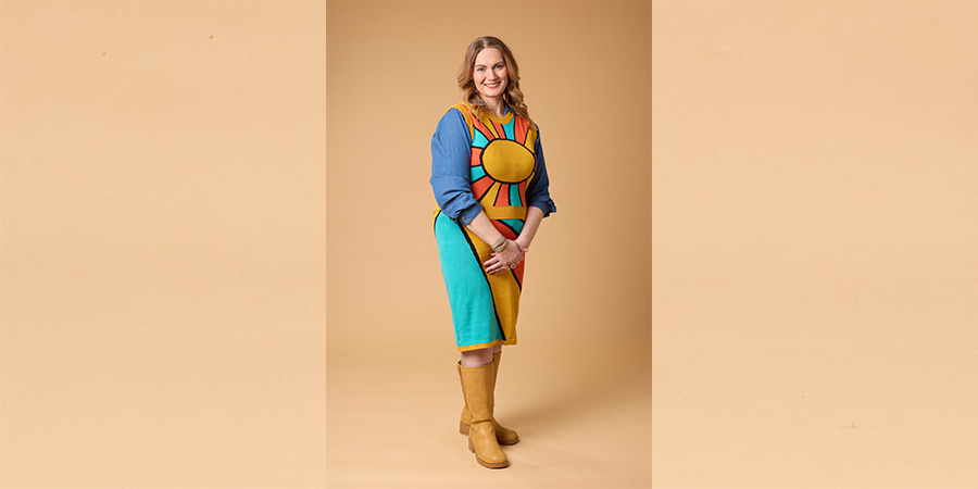 Jen poses for the COMP photo shoot. She is a white woman wearing a colorful dress.