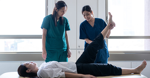 Image depticting a physical therapist, an assistant, and patient