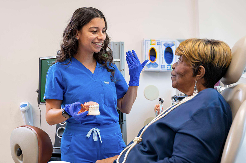 A GBMC speech-language pathologist discusses a model of the mouth and throat with a patient